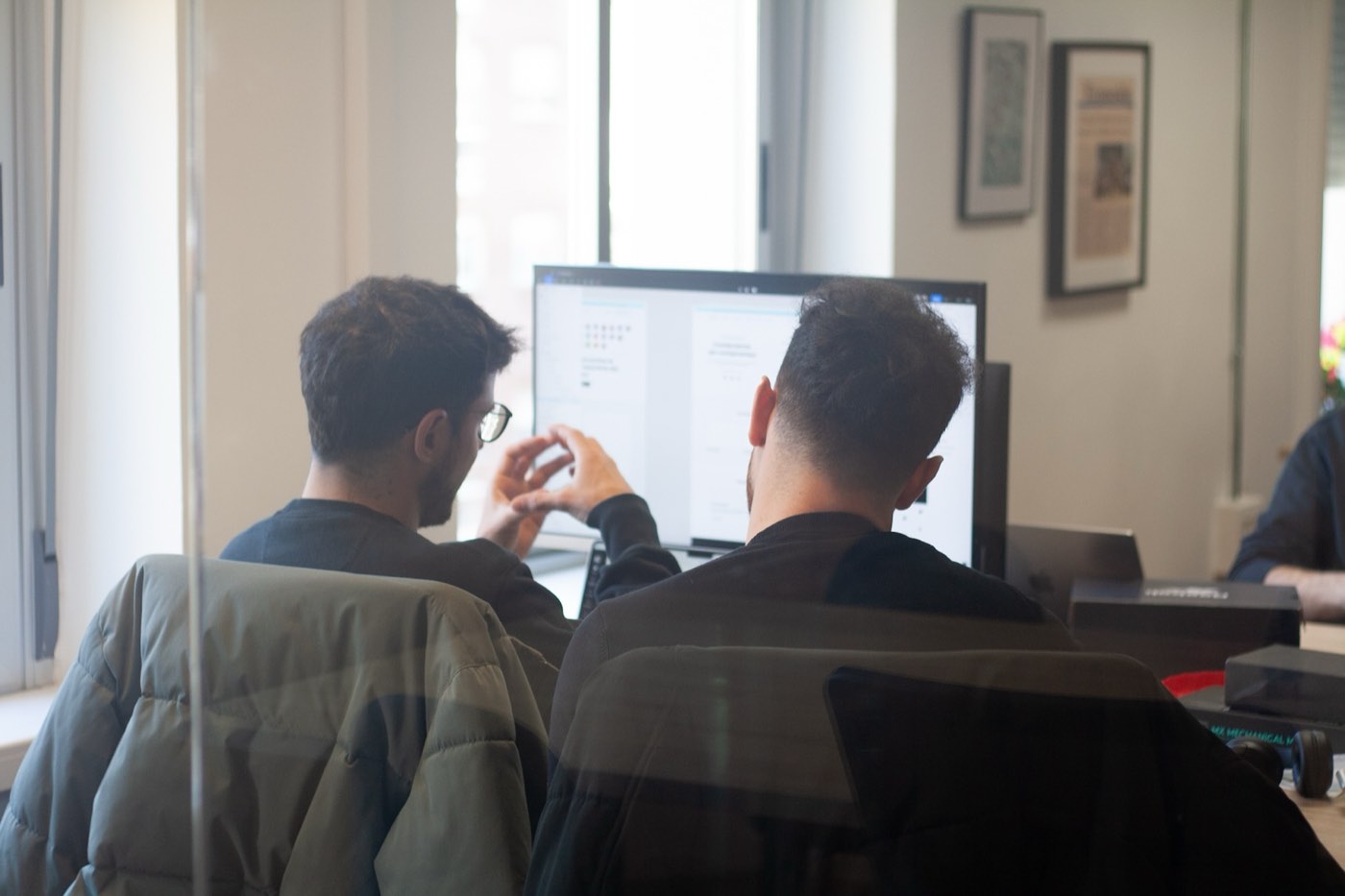 Dos diseñadores revisando pantallas en Figma frente a un monitor, en Embat